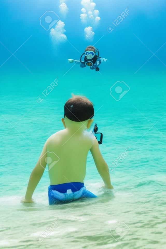 Carino piccolo bambino che indossa la maschera e pinne per le immersioni in spiaggia di sabbia tropicale.