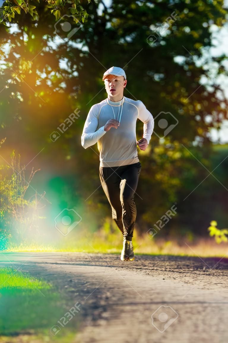 Running man joggen in de landelijke natuur op mooie zomerdag. sport fitness model Kaukasische etniciteit training buiten.