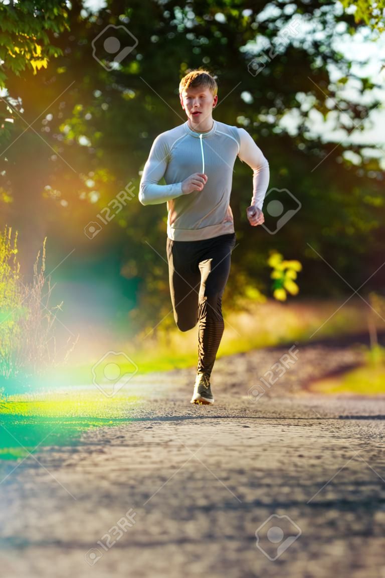 Running man joggen in de landelijke natuur op mooie zomerdag. sport fitness model Kaukasische etniciteit training buiten.