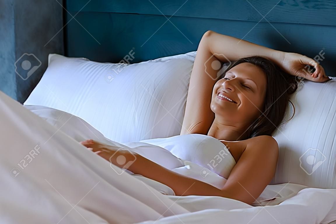 Lächelnde Mädchenbraut wachte morgens in einer Decke auf
