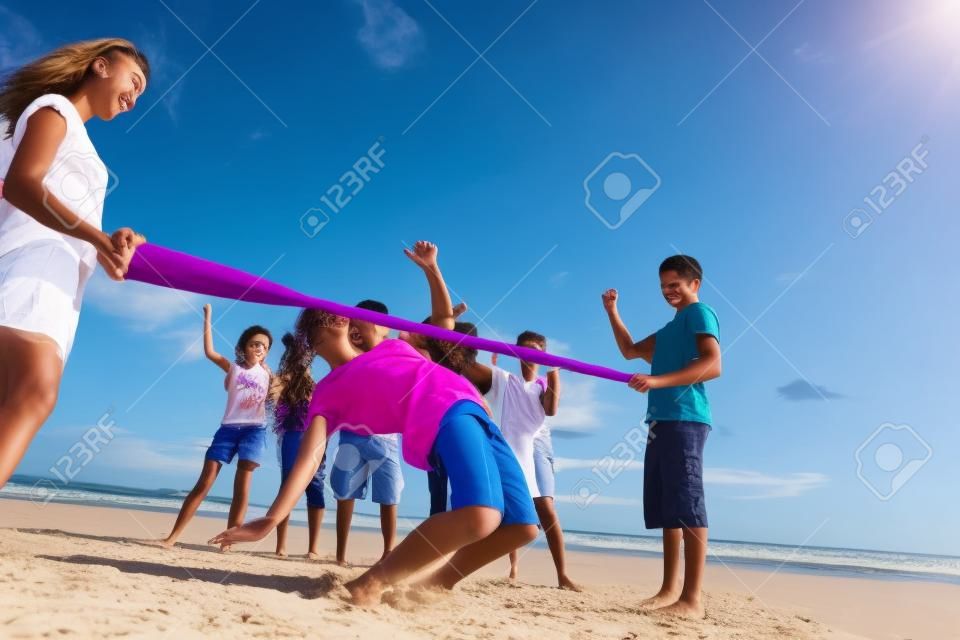 Tieners die limbo dansen op het strand