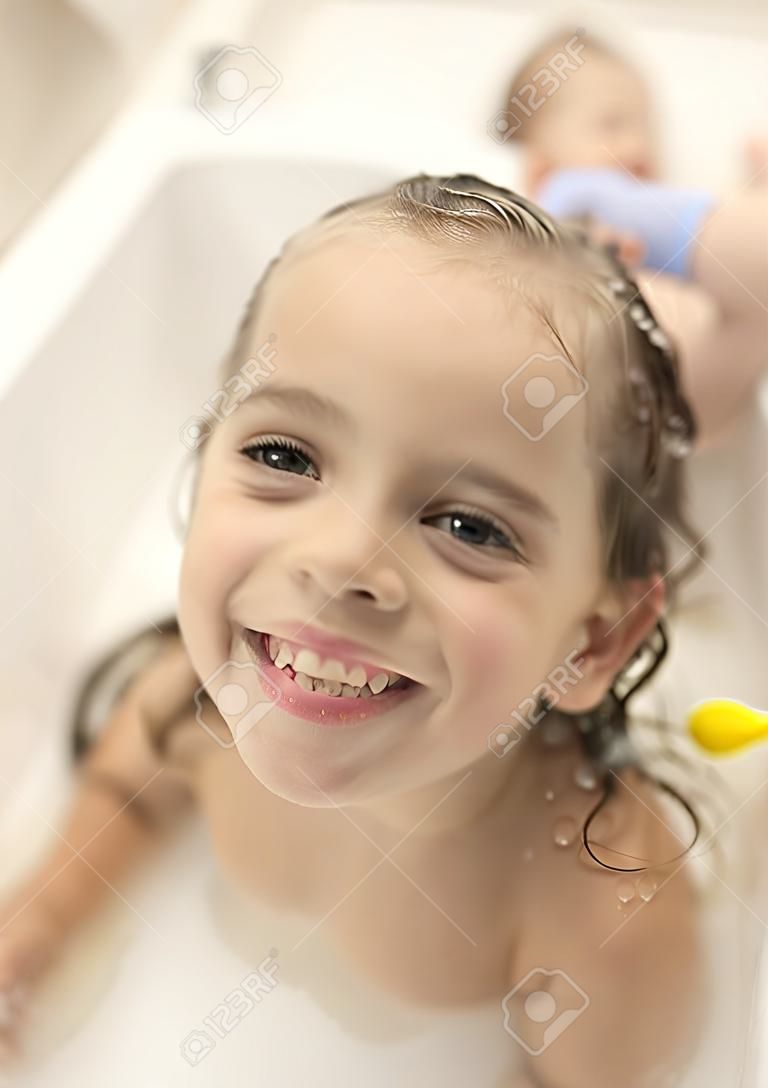 Szczęśliwe dzieci dziewczyny kąpią się w kąpieli z pianką i bąbelkami.