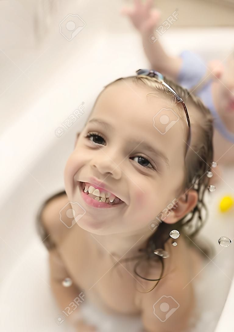 행복한 어린이 소녀들이 거품과 거품으로 목욕을 하고 있습니다.