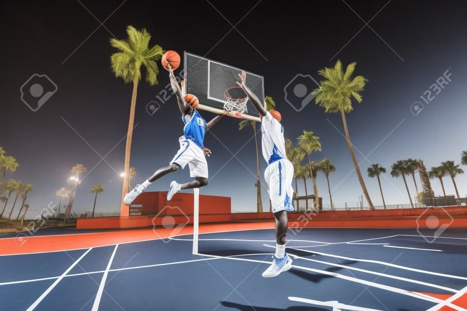 Друзья играют в баскетбол - афро-американских игроков, имеющих товарищеский матч на открытом воздухе