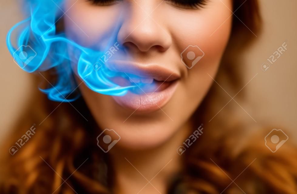 Mulher que fuma, fecha acima na fumaça e na boca