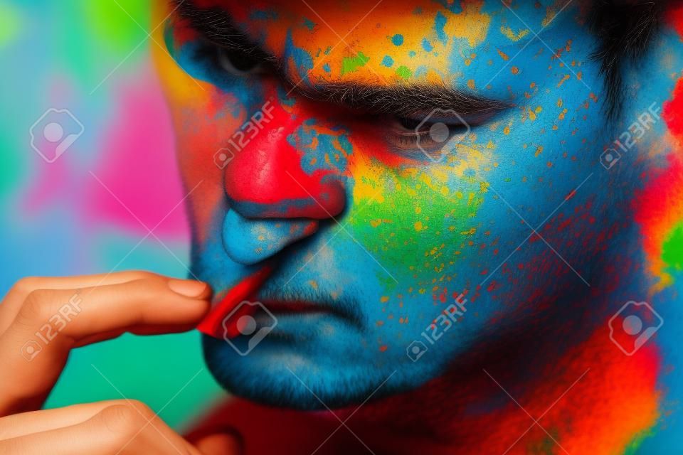 Portrait d'un homme à la mode avec une peinture colorée sur le visage
