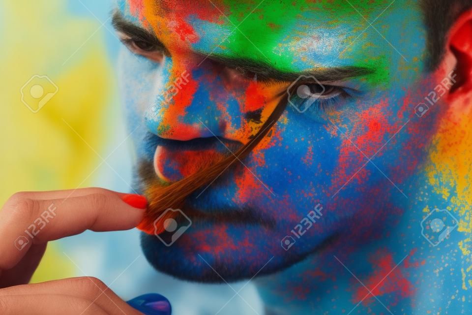 Ritratto di uomo alla moda con pittura colorata sul viso