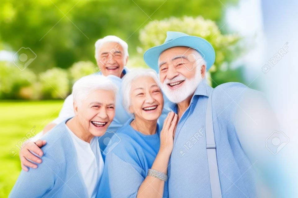 Grupa młodych seniorów bawiących się na świeżym powietrzu - czterech emerytów, którzy łączą się na świeżym powietrzu, koncepcje dotyczące stylu życia i osób starszych