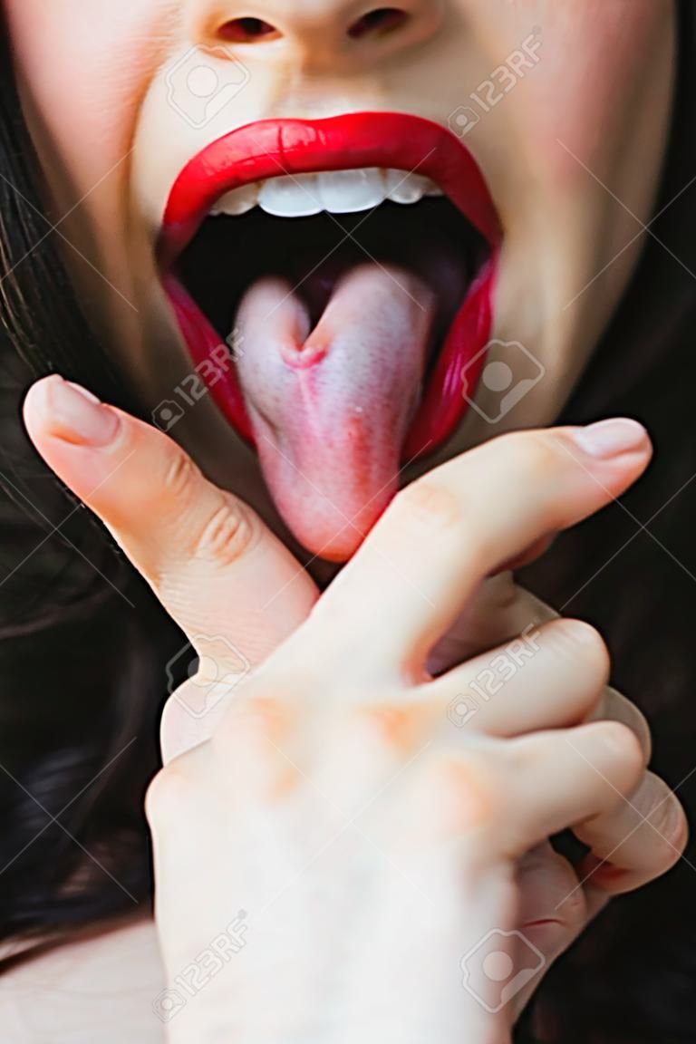 Image of a woman sticking her tongue out between the fingers