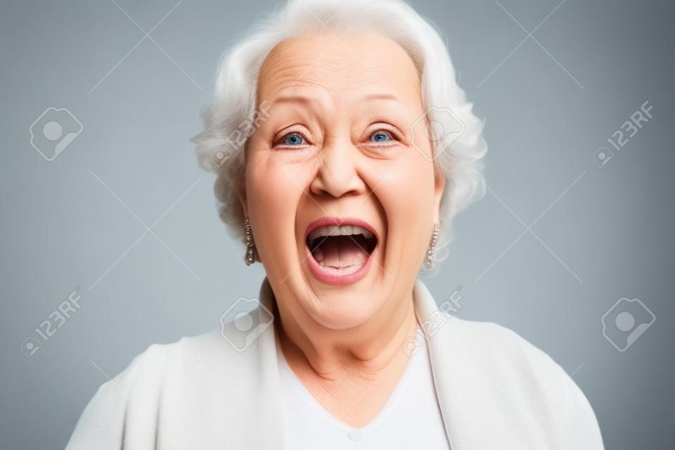 Bliska Szokujący twarzy starszy kobieta patrząc w kamerę z szeroko otwarte usta, odizolowane na białym tle.