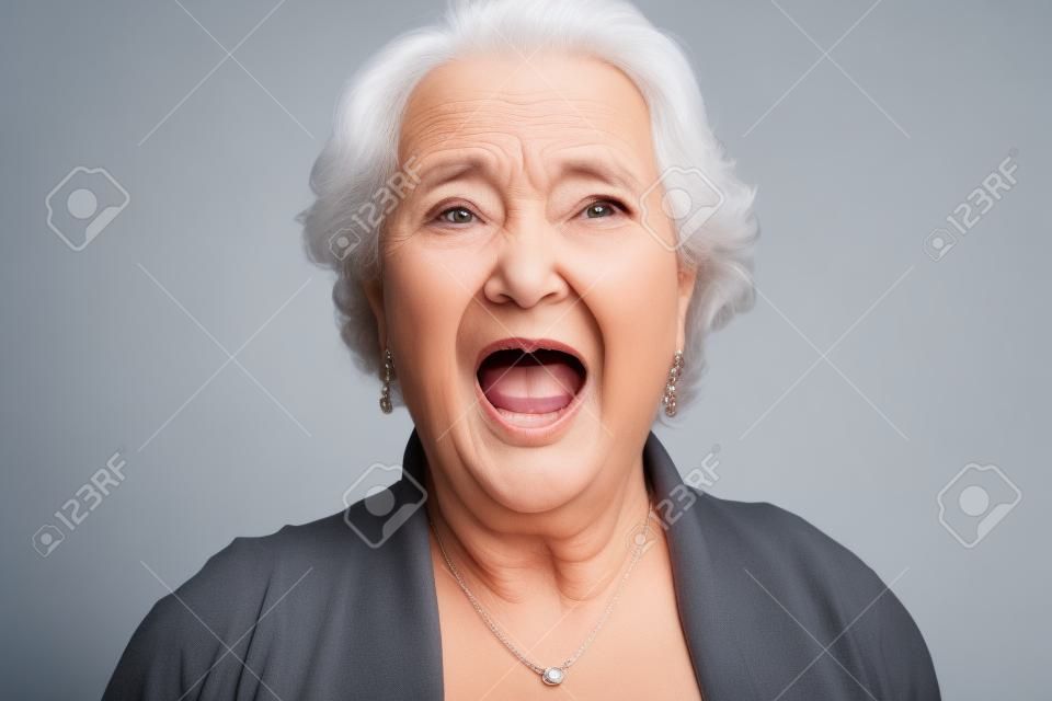 Bliska Szokujący twarzy starszy kobieta patrząc w kamerę z szeroko otwarte usta, odizolowane na białym tle.