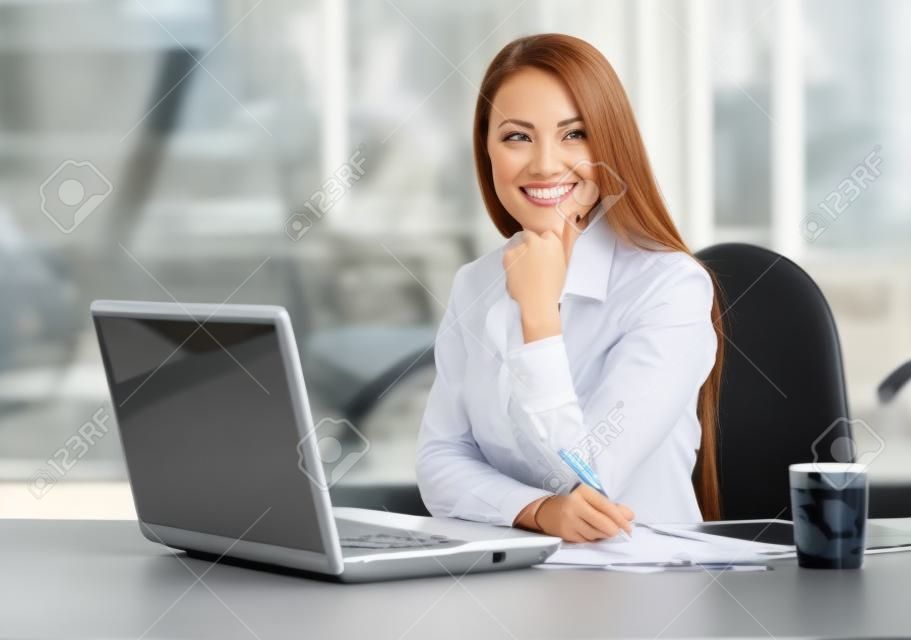 Mulher de negócios que trabalha no computador portátil no escritório