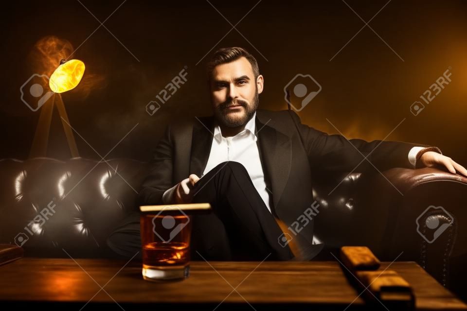 葉巻とグラスウイスキーを持つ魅力的な男