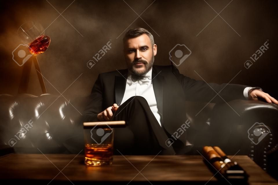 葉巻とグラスウイスキーを持つ魅力的な男