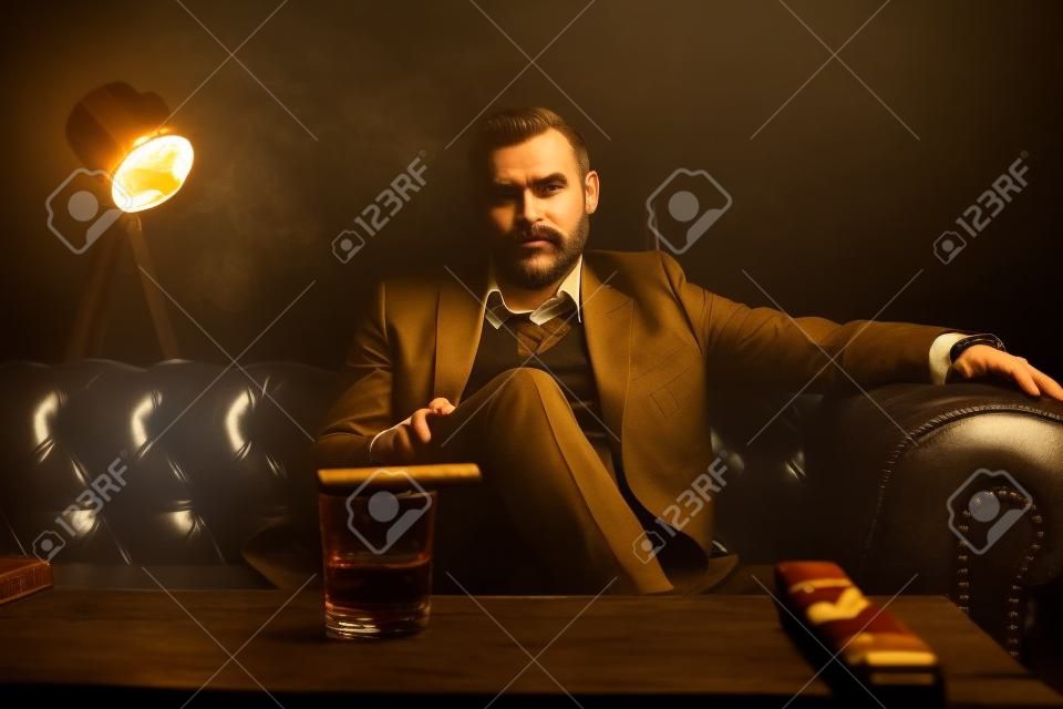 Homme attirant avec le cigare et un whisky en verre