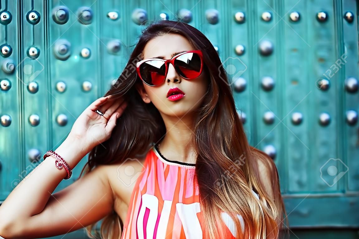 fashion beautiful girl in sunglasses standing near the turquoise walls