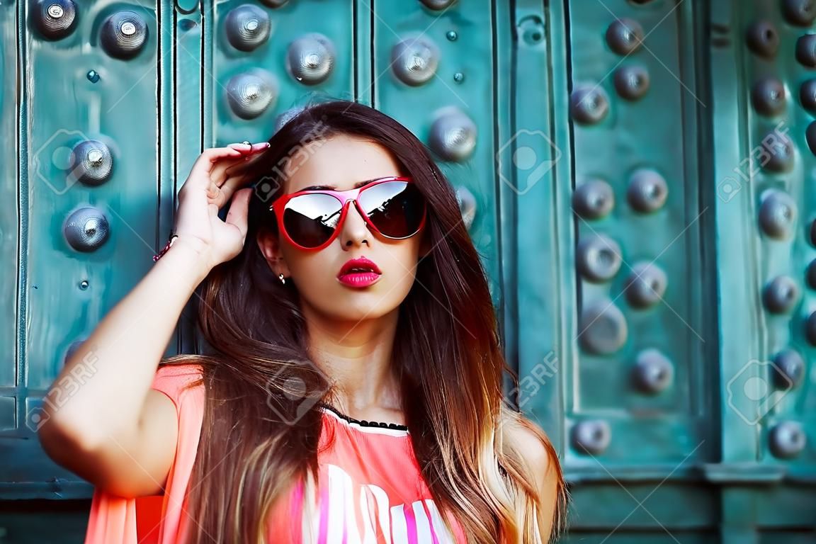 fashion beautiful girl in sunglasses standing near the turquoise walls