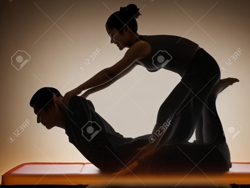 un homme et une femme perfoming massage thaï en studio silhouette sur fond blanc