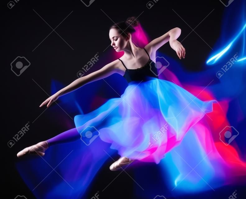 Une jeune femme de race blanche danseur de ballet danse isolé sur fond noir avec effet de vitesse de flou de peinture de lumière