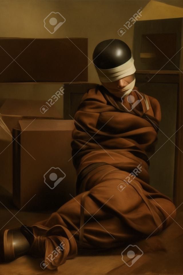 A young woman tied-up, blind folded and muted in old room. Low key setting