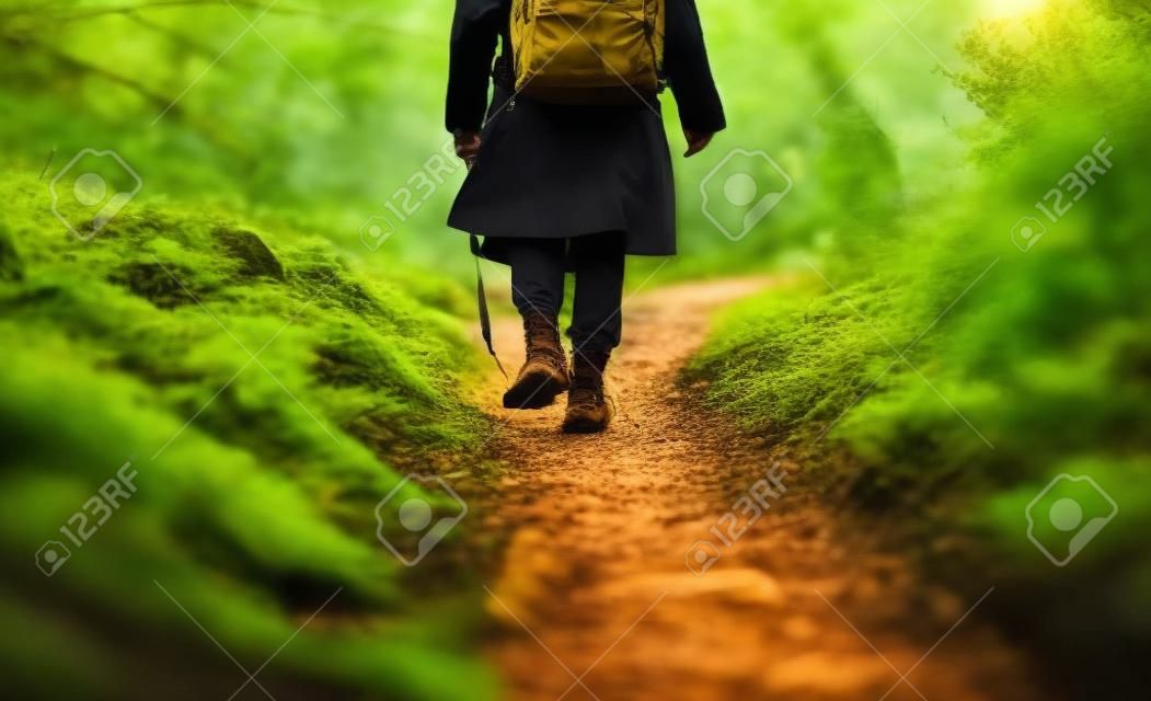 Un voyageur masculin passe par un sentier naturel, une forêt et une prairie, une heure d'or, une photographie de la nature, des bottes de trekking en gros plan, une IA générative