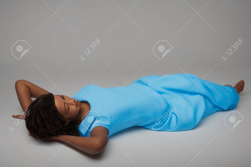 Pleine longueur femme couchée au sol sur le dos avec les mains sur la tête, d'un repos, isolé sur fond blanc