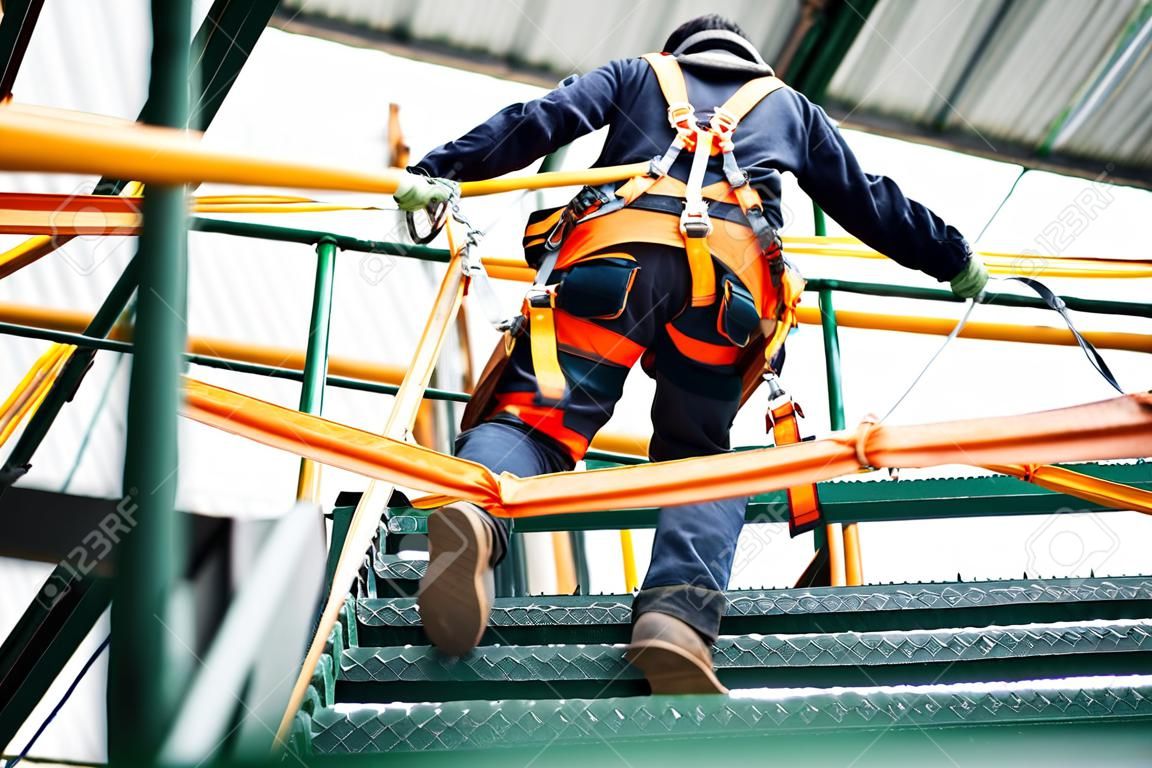 Pracownik budowlany noszący szelki bezpieczeństwa i linę bezpieczeństwa pracujący na wysokim miejscu