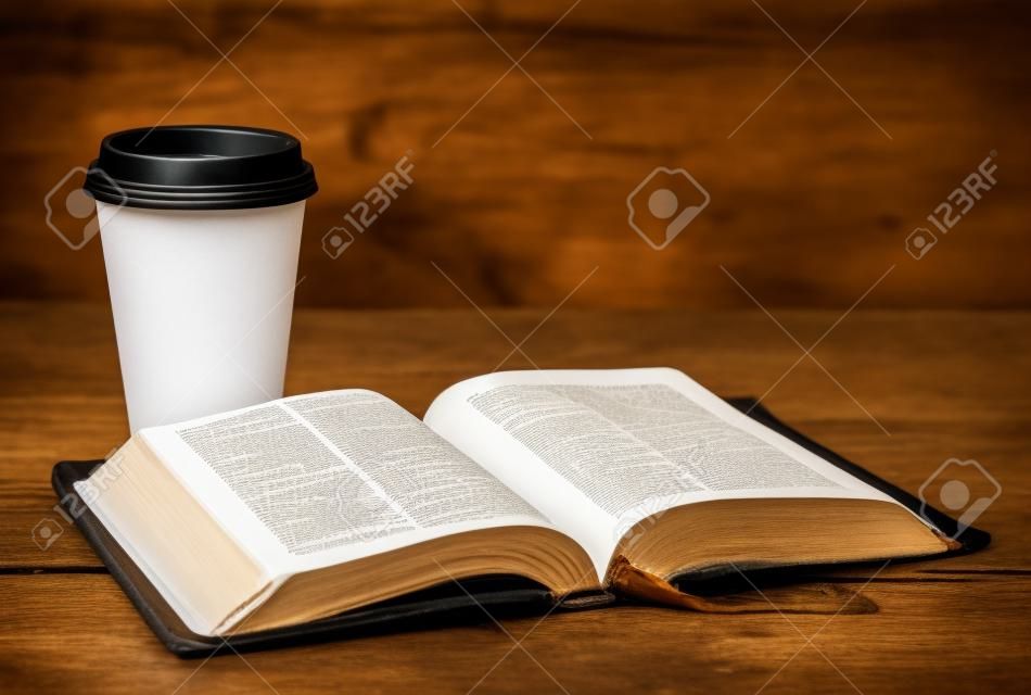 Bible and a Cup of Coffee in a Disposable Paper Cup on a Wooden Table