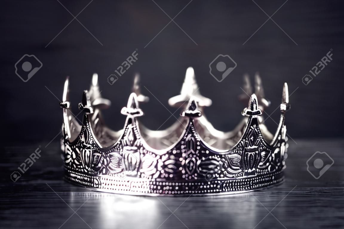 A Silver Metal King or Queens Crown on a black Wood Table