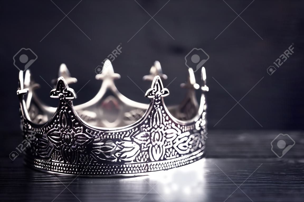 A Silver Metal King or Queens Crown on a black Wood Table