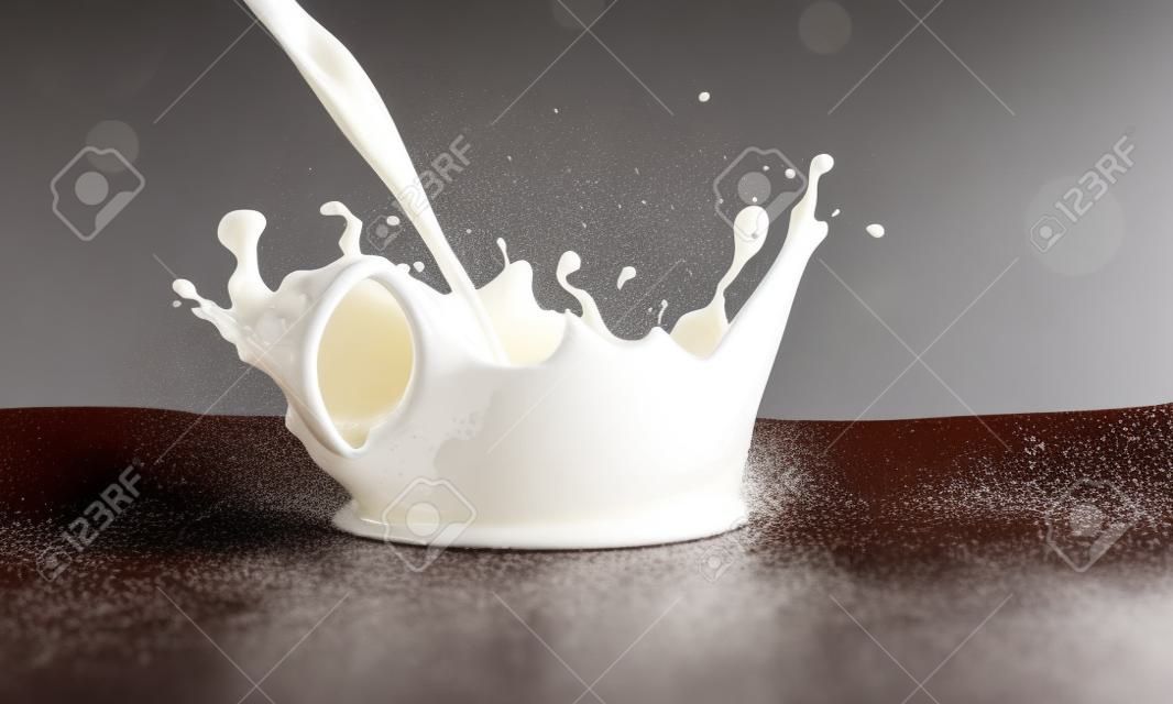 versando il latte bevanda spruzzi in latte su uno sfondo di cioccolato