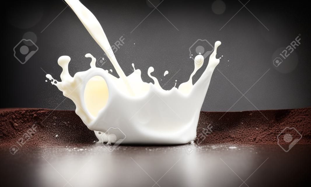 versando il latte bevanda spruzzi in latte su uno sfondo di cioccolato