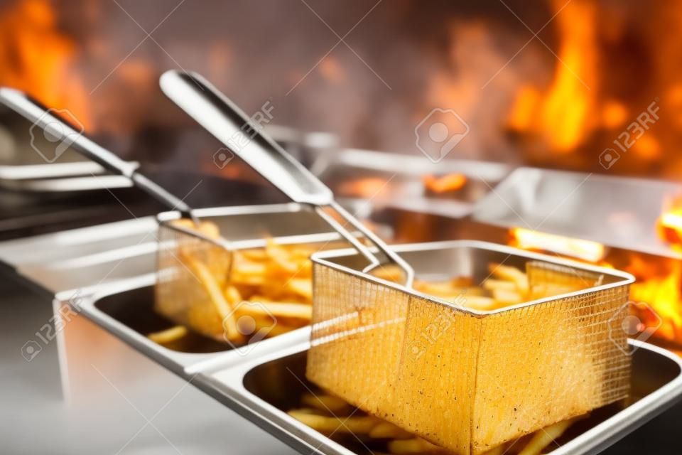 French fries cooking. Grid with strips hop potato lowered into boiling oil. Concept of fast food, delicious food, restaurant