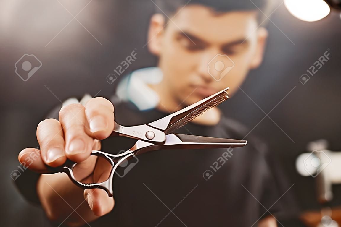 Barber shop. Close-up of barber holds clip-on hair clipper barbershop