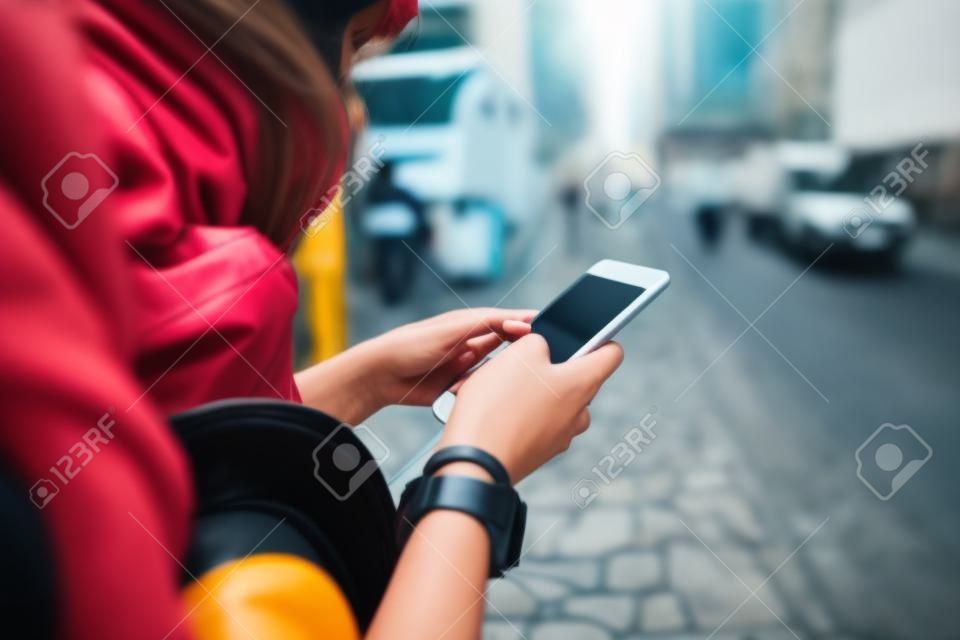 Young female tourist lost landmark in city, uses phone as navigator. Travel concept.