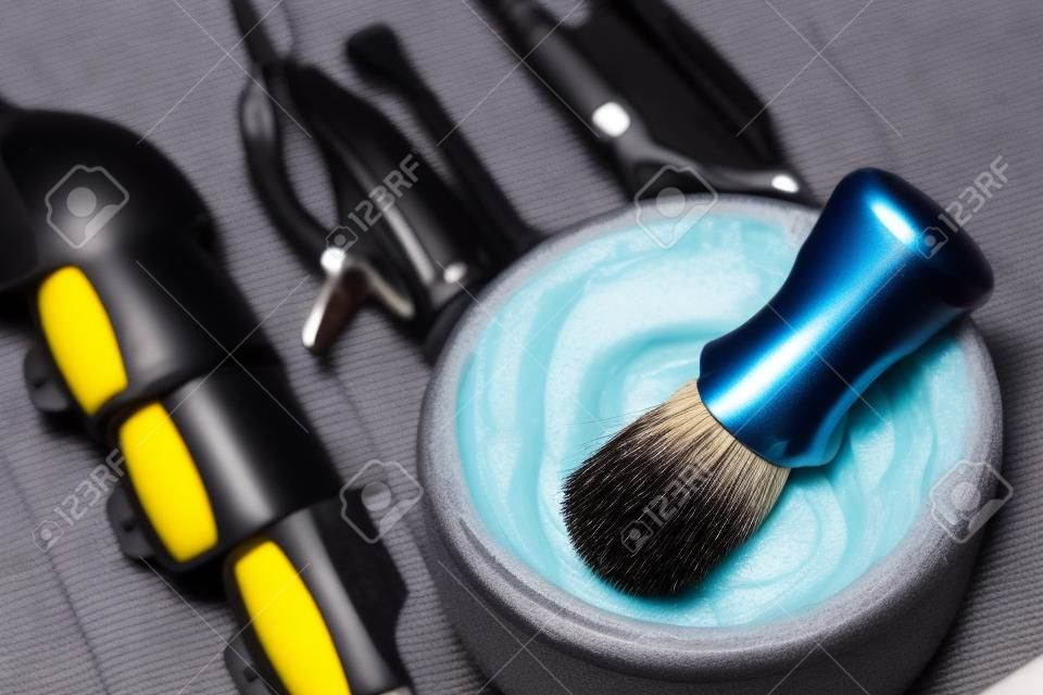 Brush for applying foam on beard man shaving with razor in barbershop background of tools