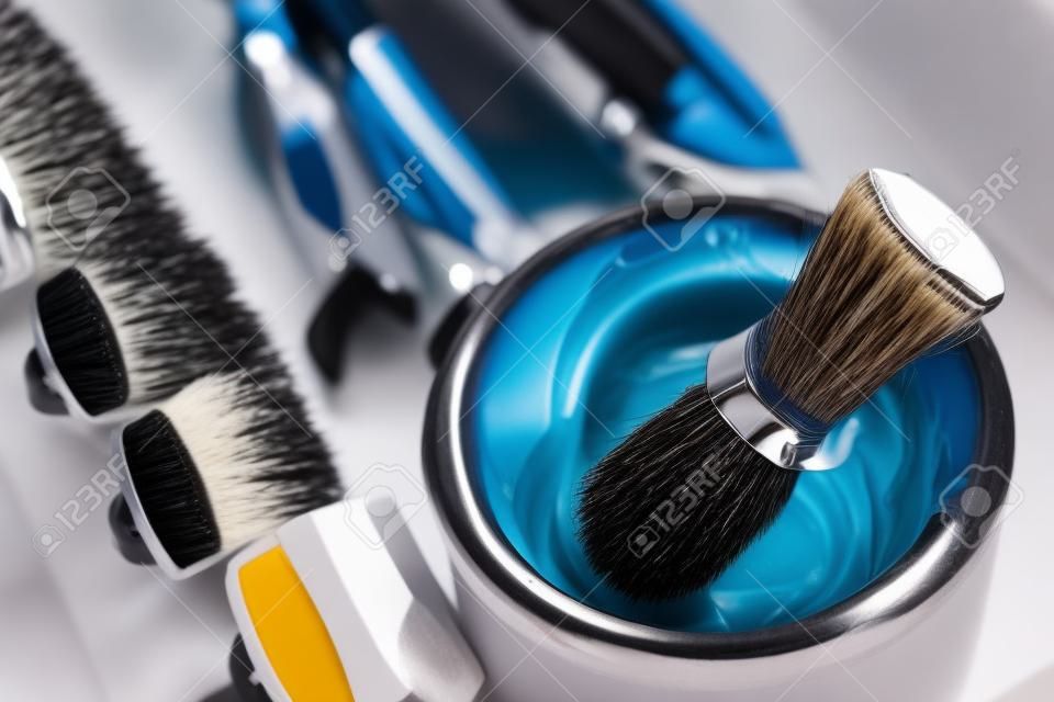 Brush for applying foam on beard man shaving with razor in barbershop background of tools