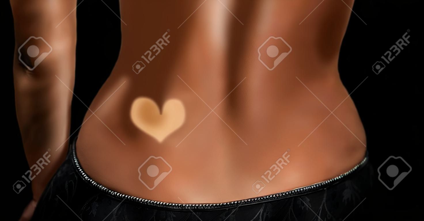 Woman body paint heart liquid tan spray with airbrush in professional beauty salon