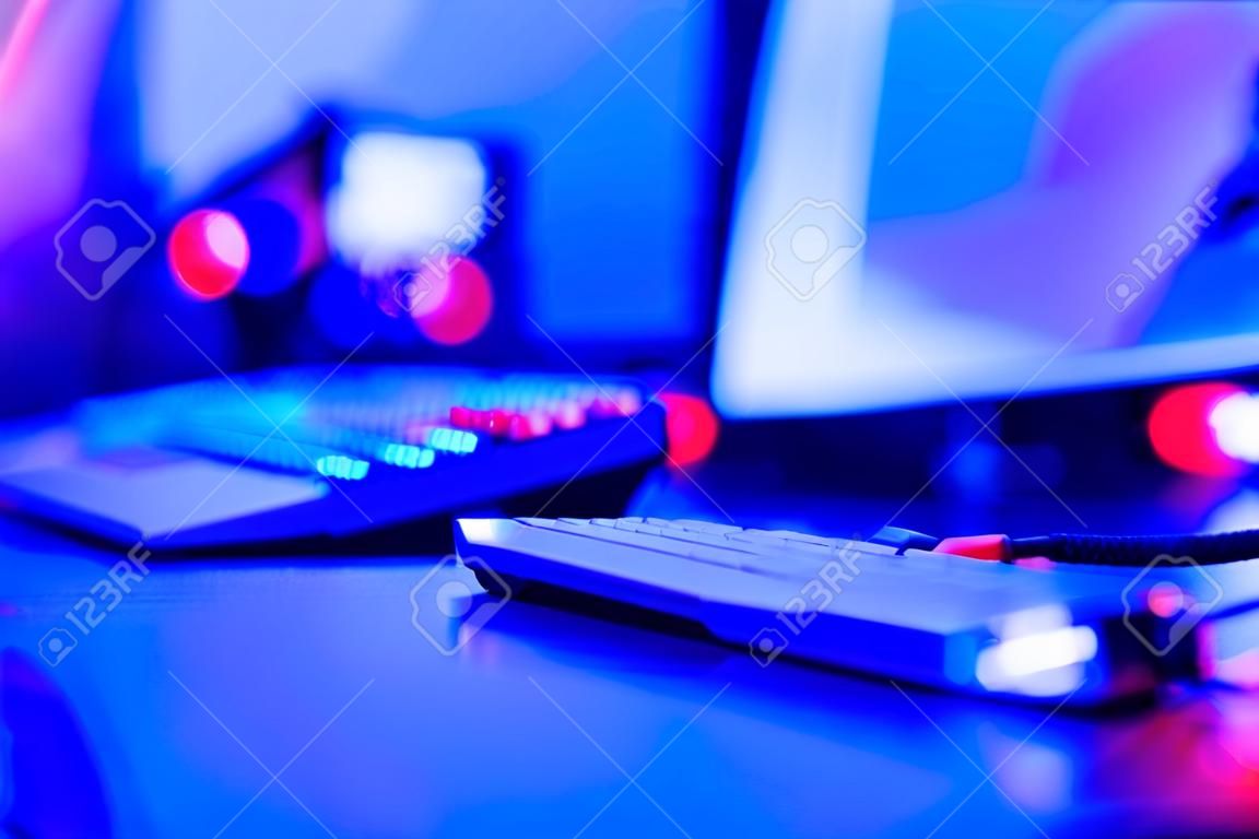 Unscharfer Hintergrund professioneller Gamer, der Turniere online spielt Computer mit Kopfhörern, rot und blau