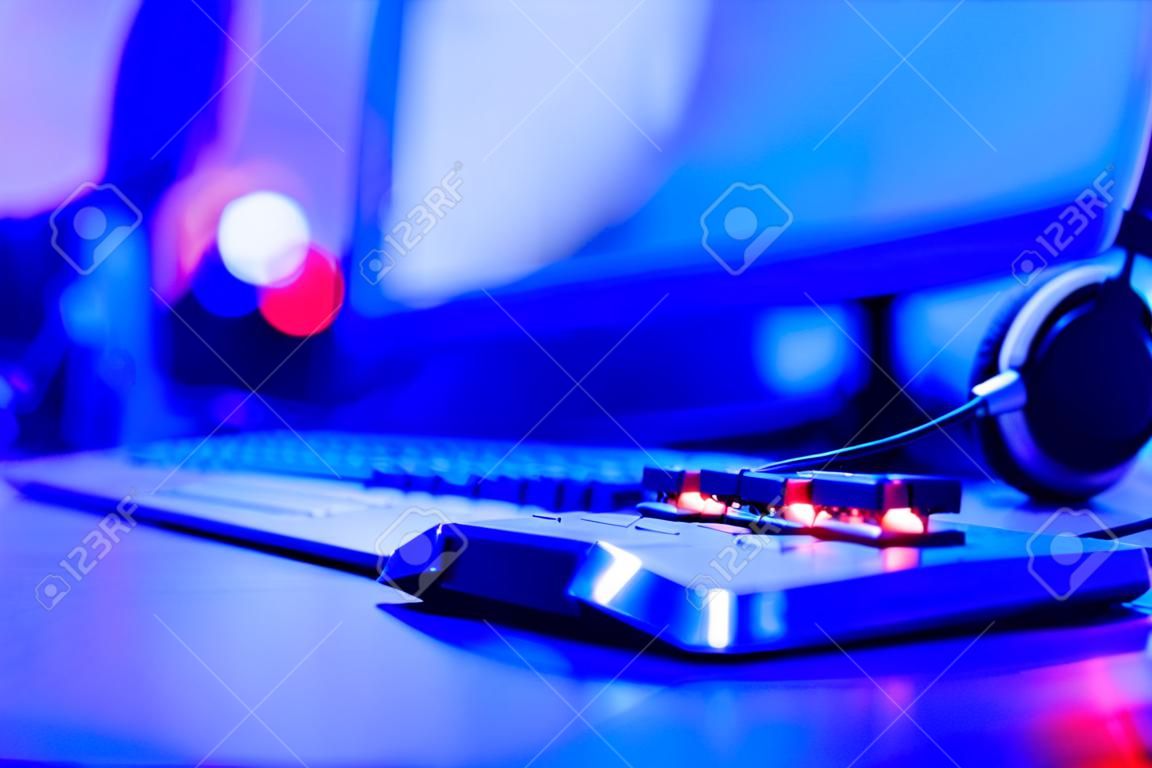 Unscharfer Hintergrund professioneller Gamer, der Turniere online spielt Computer mit Kopfhörern, rot und blau