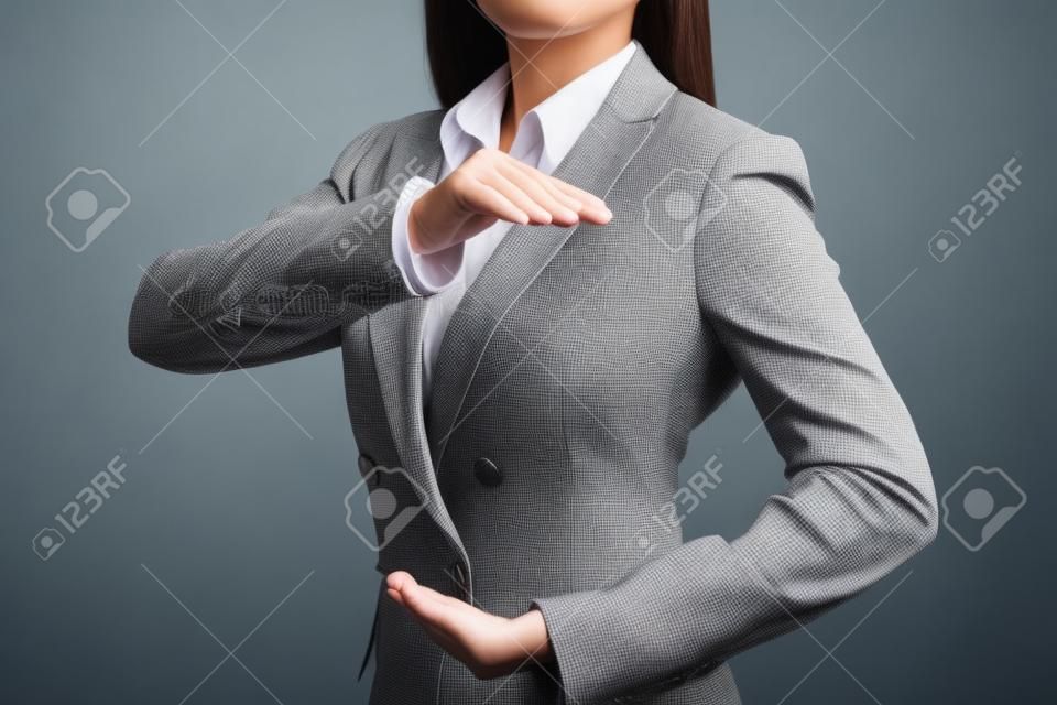 Attractive professional female hands in classic suit show protecting something. Businesswoman standing with black background. Property insurance and security concept