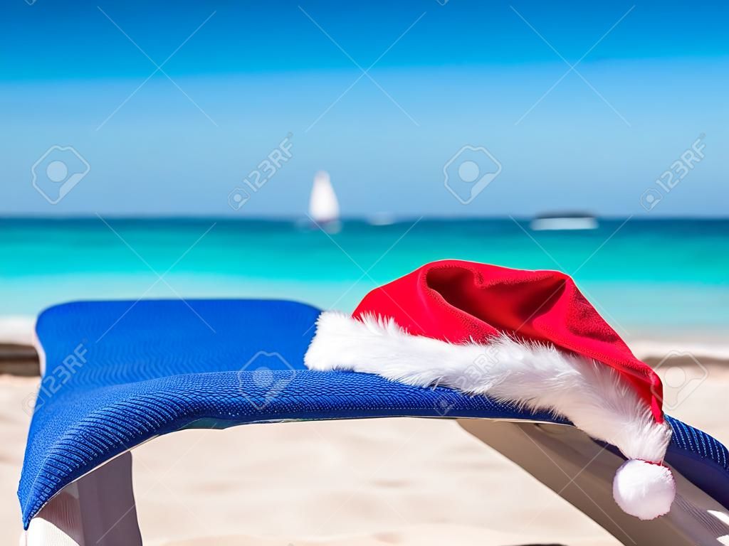 Santa Claus Hat on sandy beach. Tropical New year celebration. Nobody
