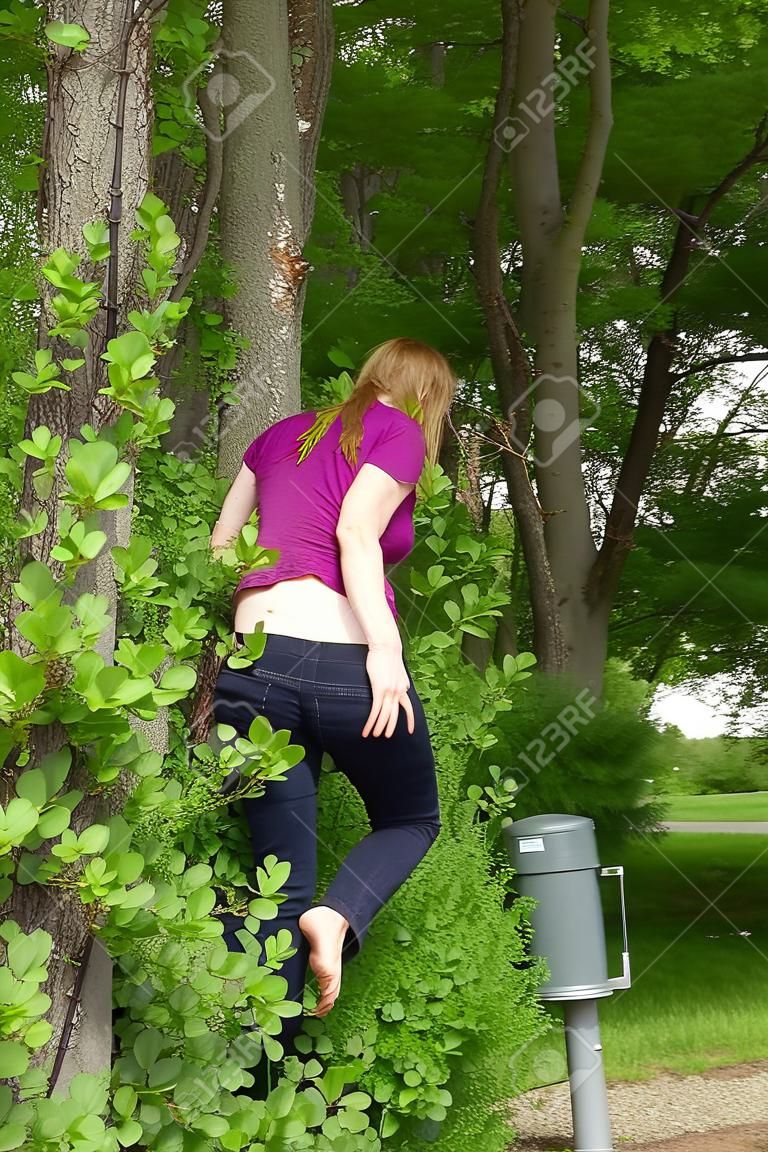 mujer está orinando al aire libre detrás de los arbustos