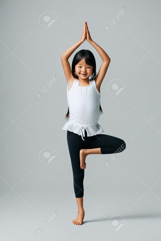 Piccola ragazza asiatica facendo esercizi di yoga isolato su bianco