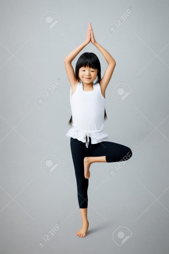 Piccola ragazza asiatica facendo esercizi di yoga isolato su bianco