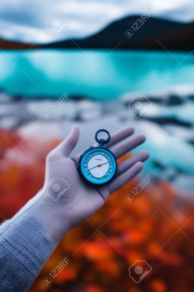 Chronomètre à main à l'extérieur, automne, lac bleu flou en arrière-plan