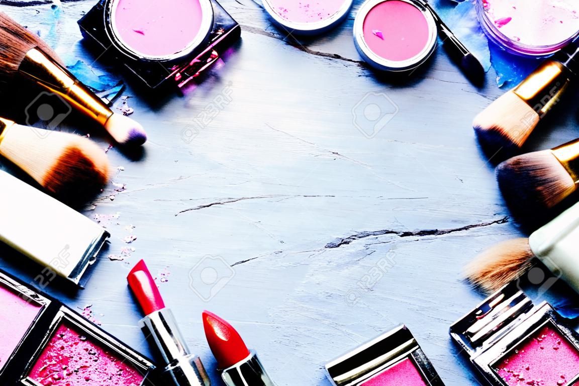 Kleurrijk frame met diverse make-up producten op donkere achtergrond