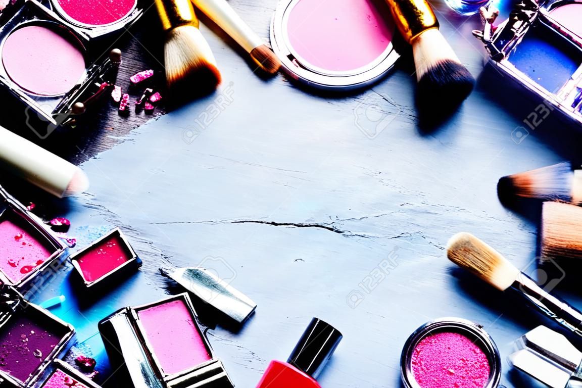 Kleurrijk frame met diverse make-up producten op donkere achtergrond