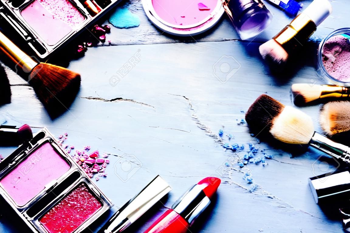 Cadre coloré avec divers produits de maquillage sur un fond sombre