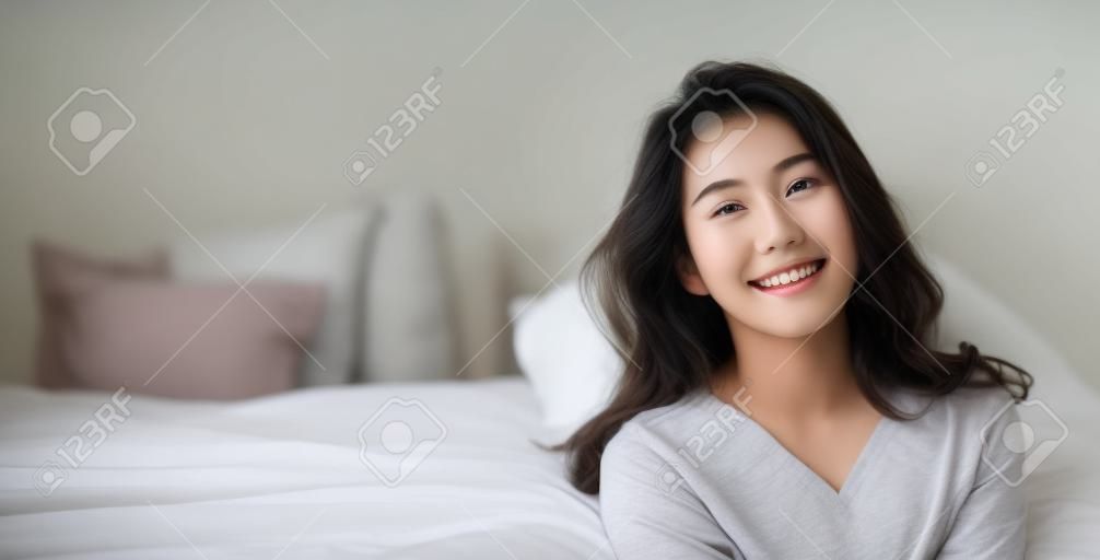 Portret młodej pięknej kobiety azjatyckich relaks w jej sypialni. Uśmiech szczęśliwa azjatykcia nastolatka odizolowywająca na białym tle sztandar.